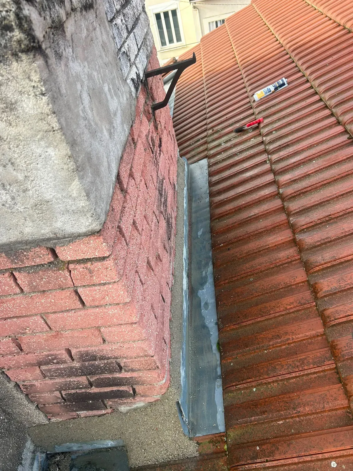 Bande de zinc neuve posée le long d'une souche de cheminée en brique, toiture en tuiles à Villejuif
