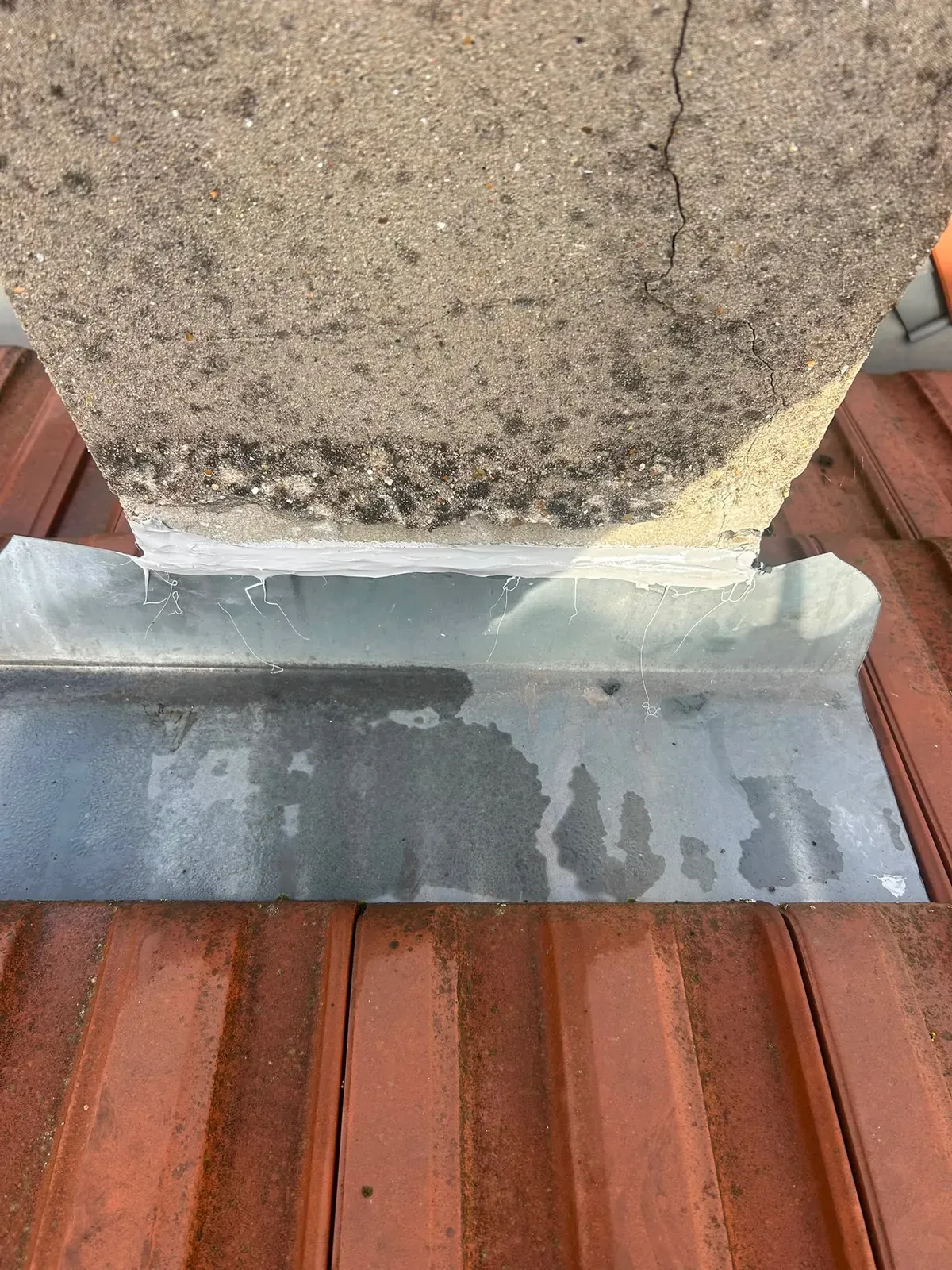 Bavette en zinc qui renvoie l'eau de pluie sur les tuiles au pied d'une cheminée à Villejuif
