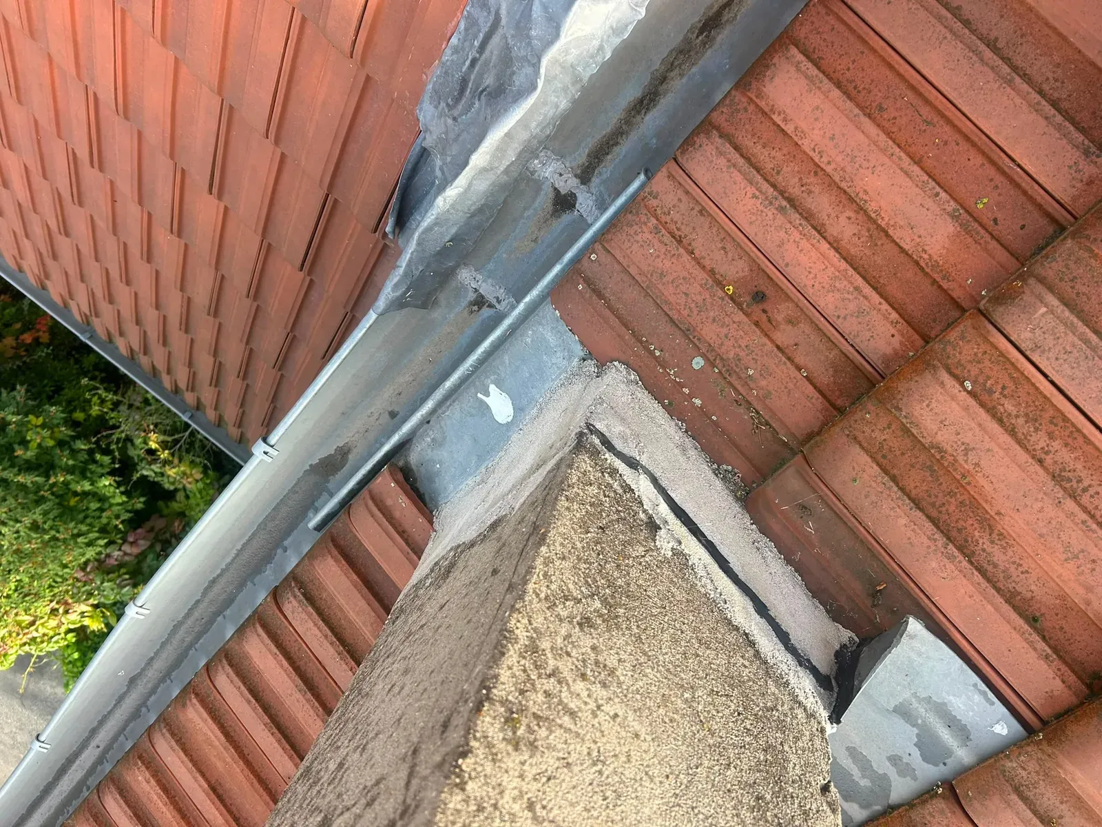 Bavette en zinc neuve au pied d'une souche de cheminée enduite sur une toiture en tuiles à Villejuif