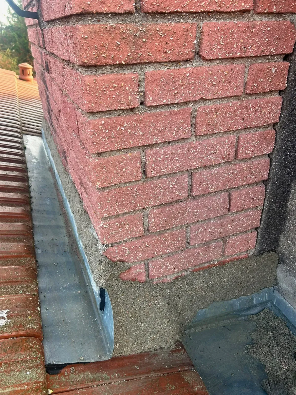 Angle d'une souche de cheminée en brique avec zinc façonné et raccord au mortier à Villejuif